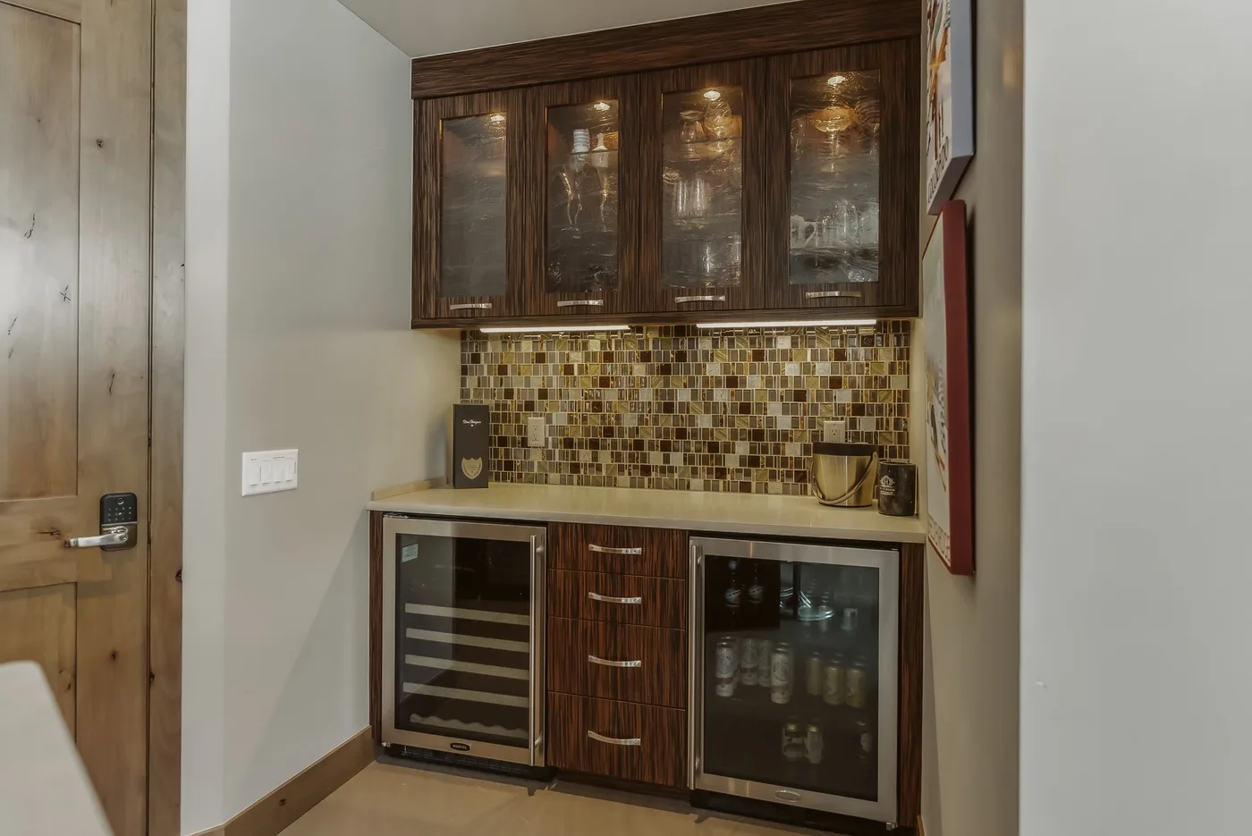 A compact bar area with dark cabinets, a tiled backsplash, and built-in beverage coolers.