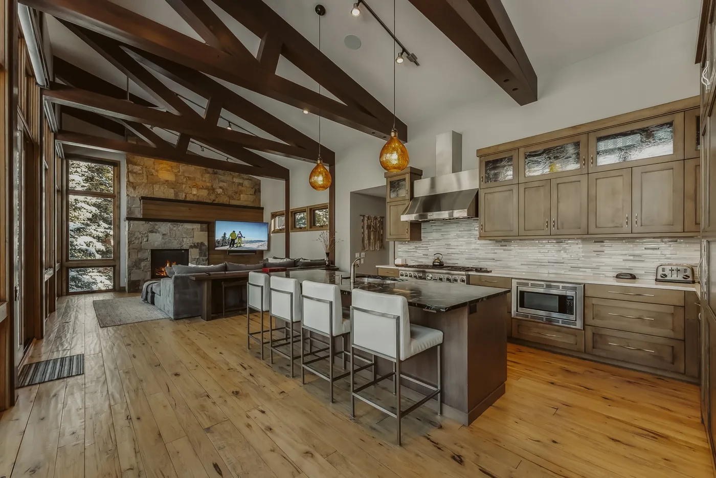 An open kitchen and dining area with a central island beneath exposed ceiling beams.