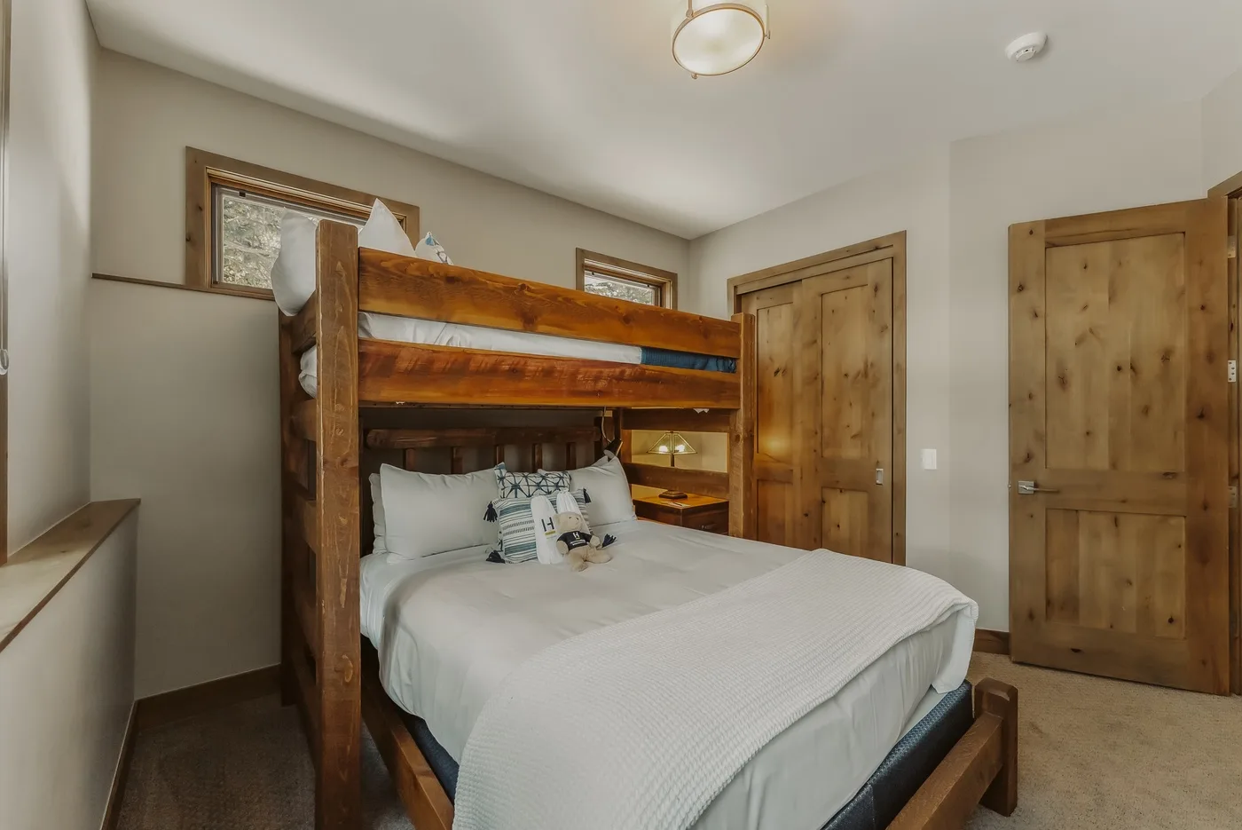 A bedroom with a wooden bunk bed above a neatly made lower bed.