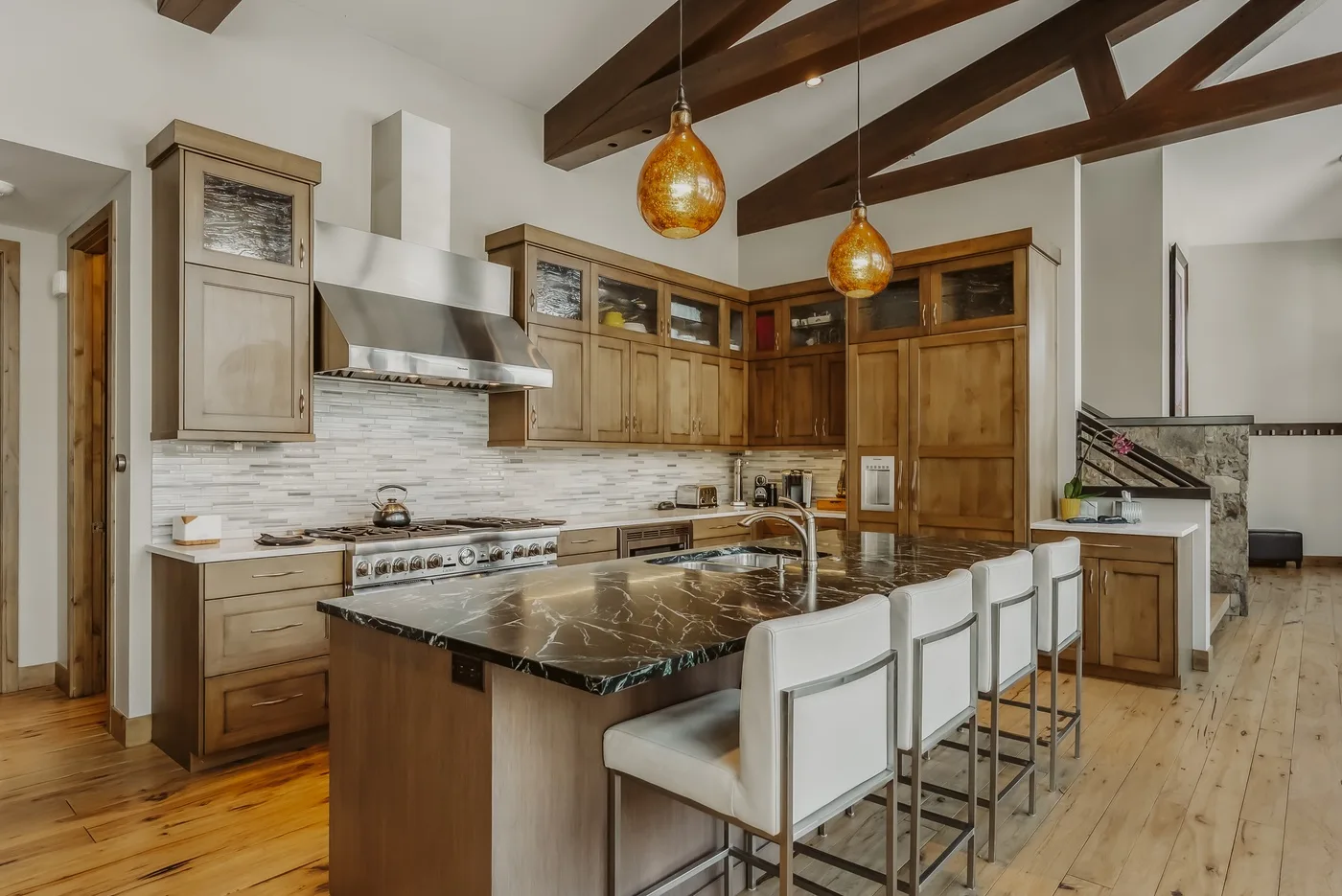 A spacious kitchen with wooden cabinets, a central island, and pendant lights.