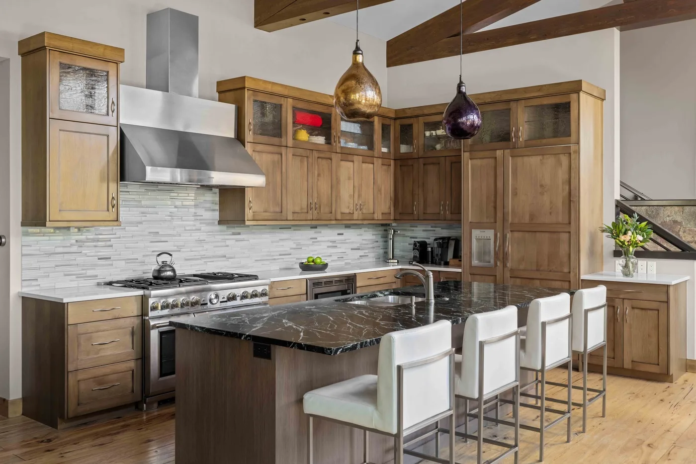 A kitchen with wooden cabinetry, a central island, and white bar seating.