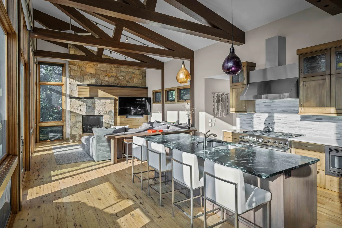 An open-plan kitchen and living area with a stone island and seating.