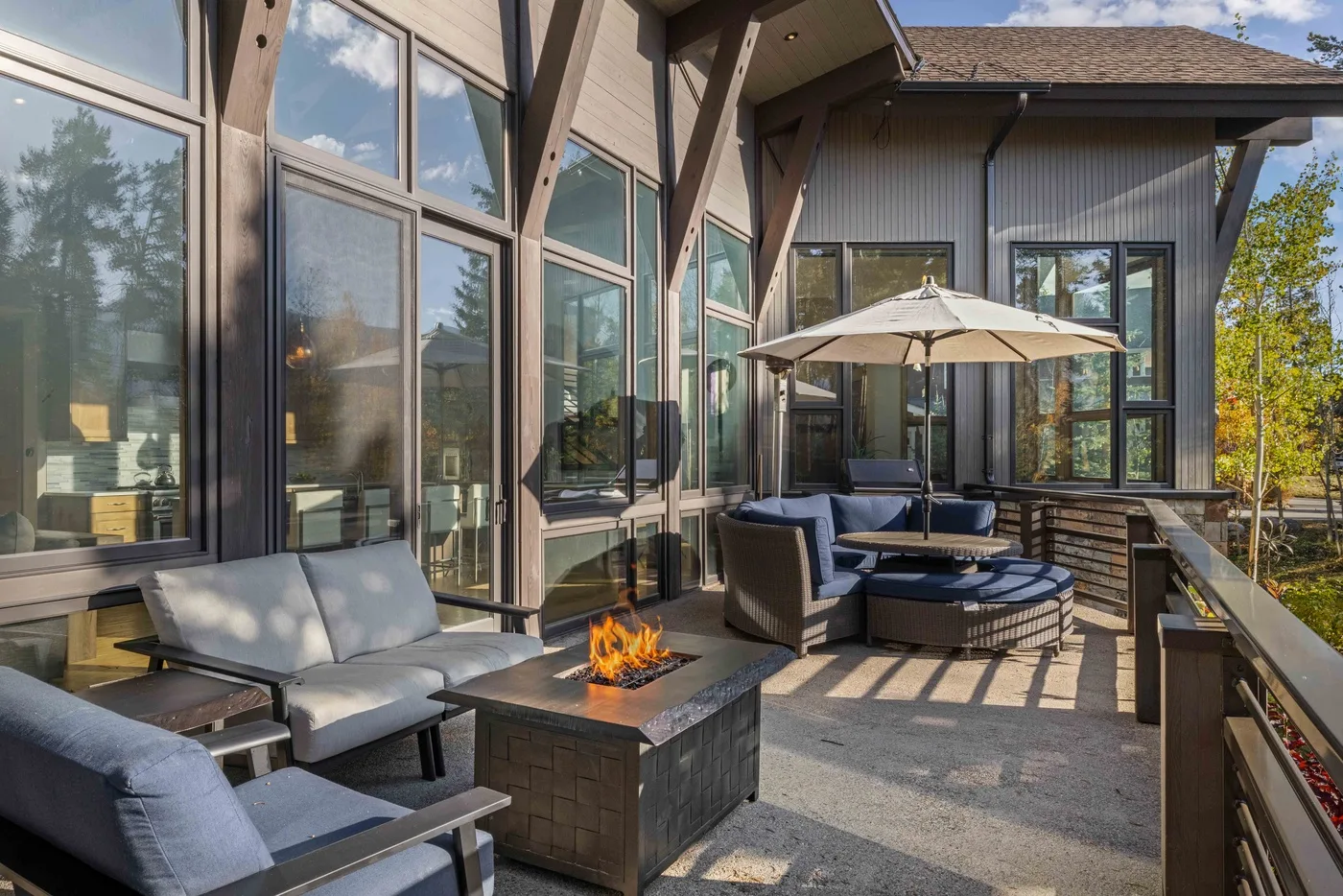 An outdoor patio with seating, a fire table, and a large umbrella.