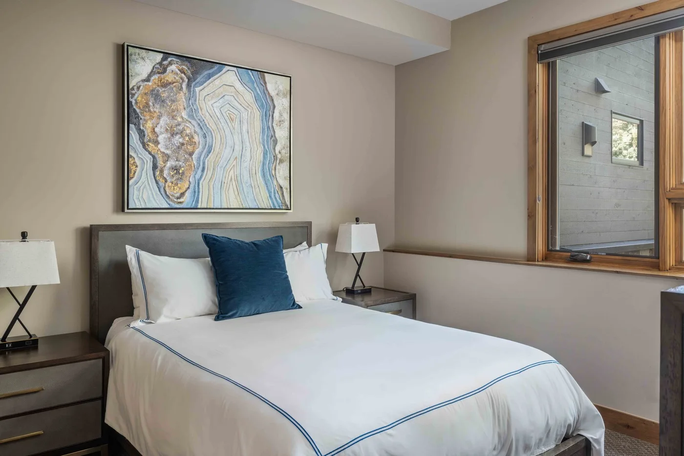 A bedroom with a neatly made bed and framed artwork above the headboard.