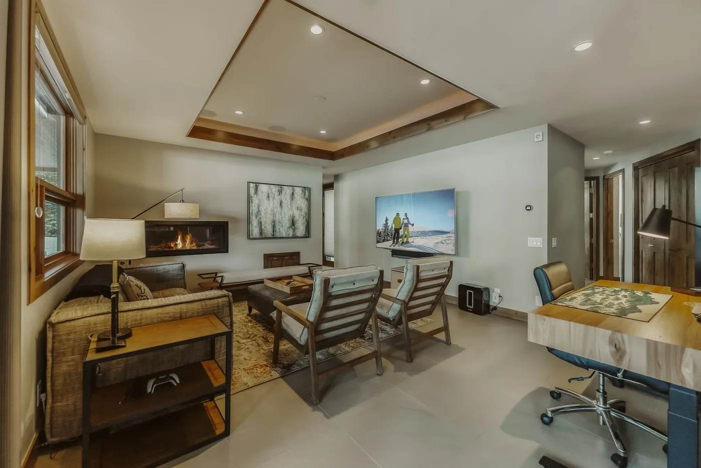 A living and dining area with seating, a table, and wall-mounted televisions.