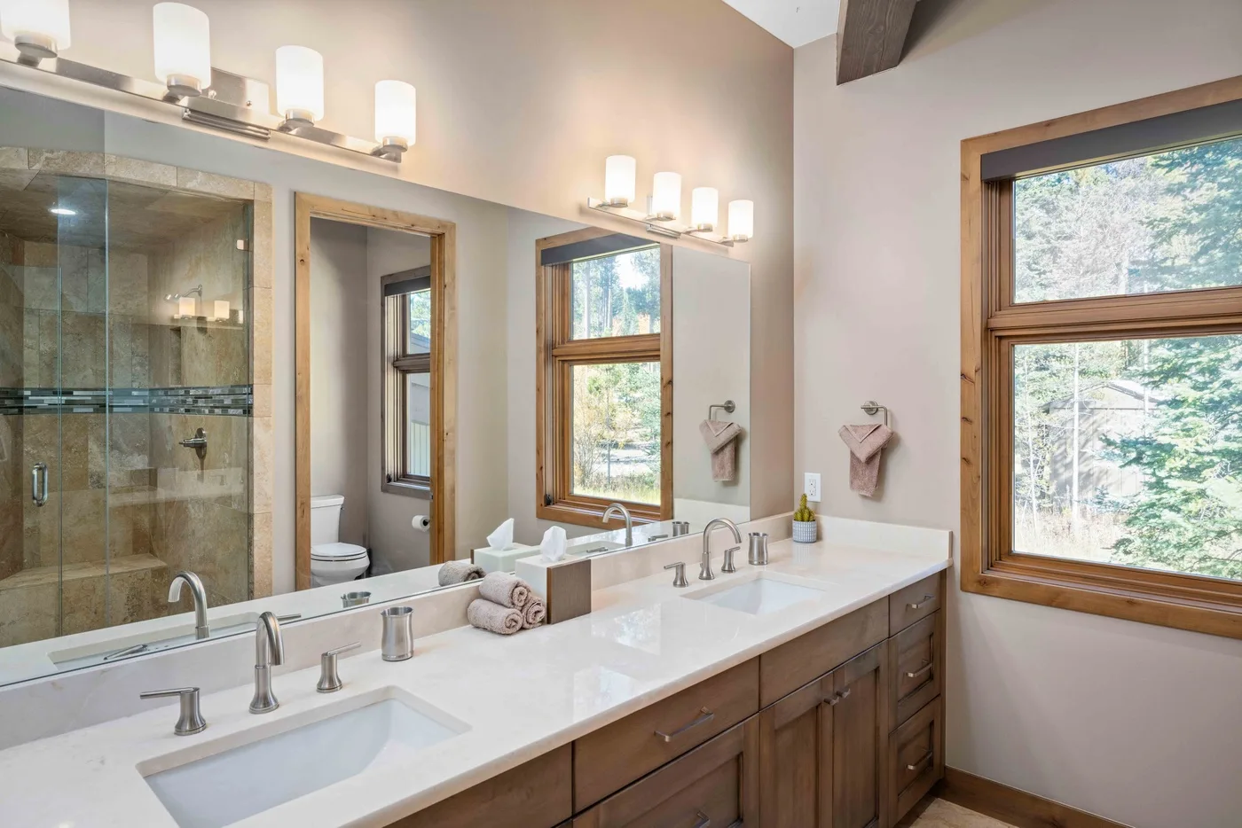 Bathroom vanity with a long countertop, mirrors, and windows.