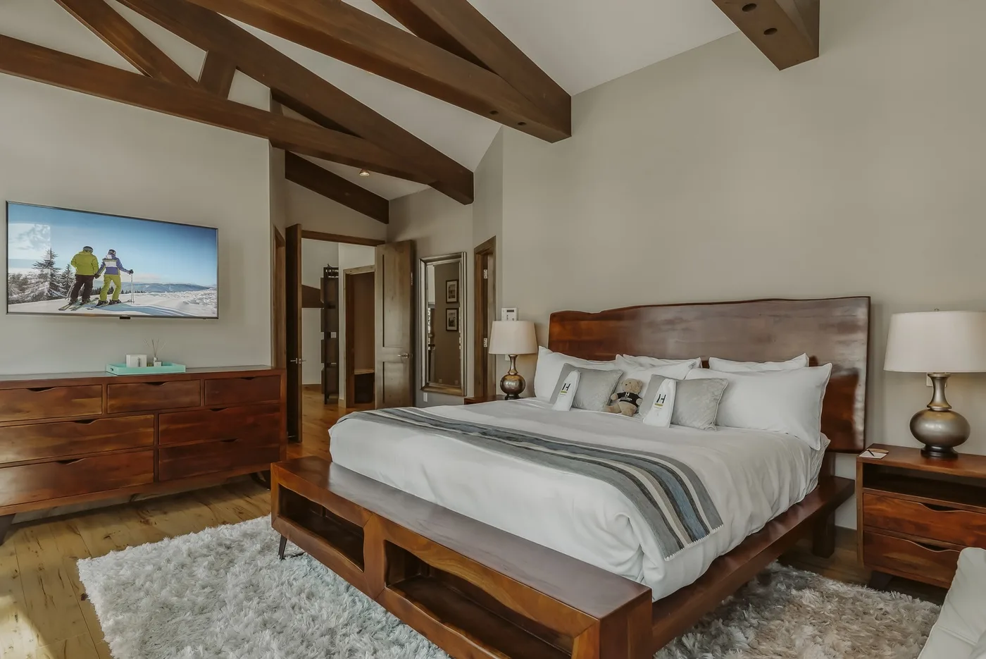 A bedroom with a large bed, wooden furnishings, and exposed ceiling beams.