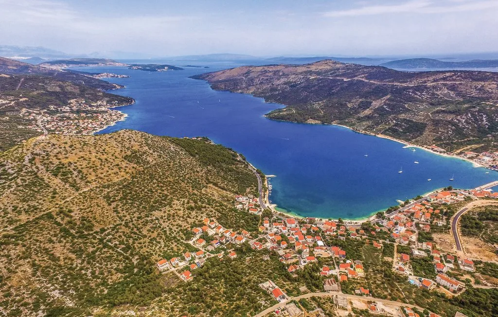 Vista aérea de una bahía costera rodeada de colinas y asentamientos junto a la costa.