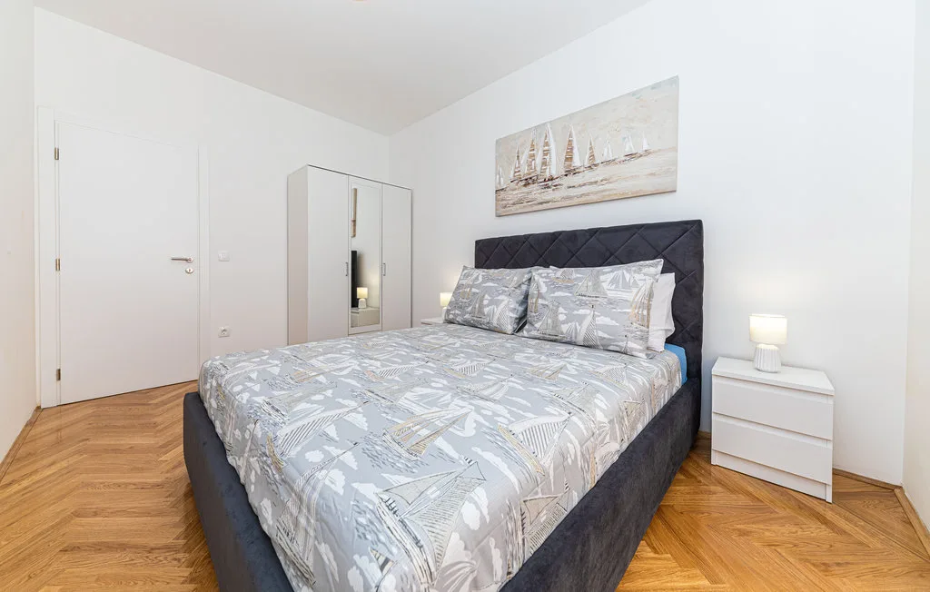 Un dormitorio con una cama doble, ropa de cama estampada y un cuadro sobre el cabecero.