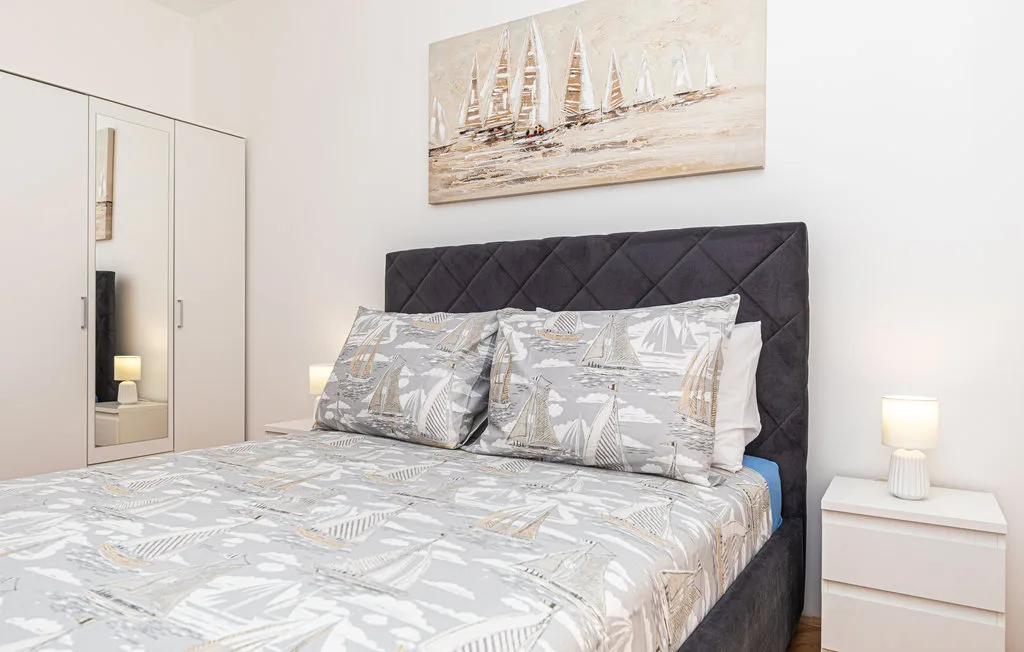 Un dormitorio con una cama tendida y ropa de cama con motivos de veleros.