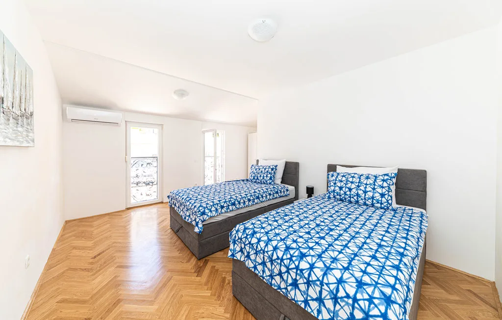 Un dormitorio luminoso con dos camas vestidas con ropa de cama estampada en azul y blanco.