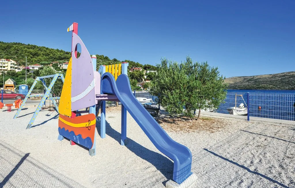 Un parque infantil al aire libre con una estructura colorida y un tobogán junto al agua.
