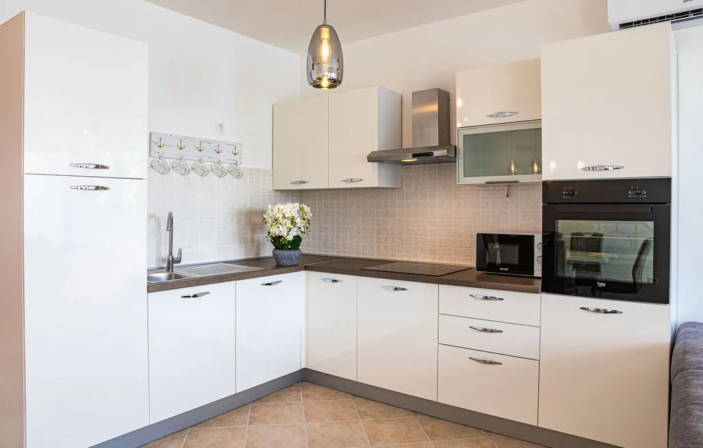 Una cocina moderna y luminosa con gabinetes blancos y un salpicadero de azulejos.