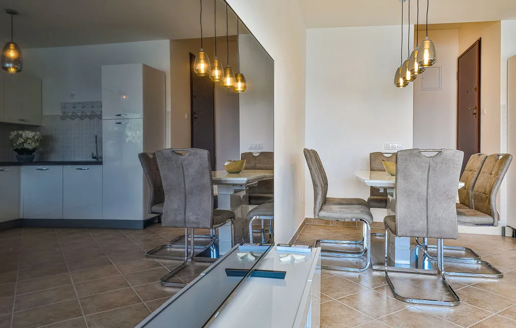 A dining area with a table, upholstered seating, and pendant lights.