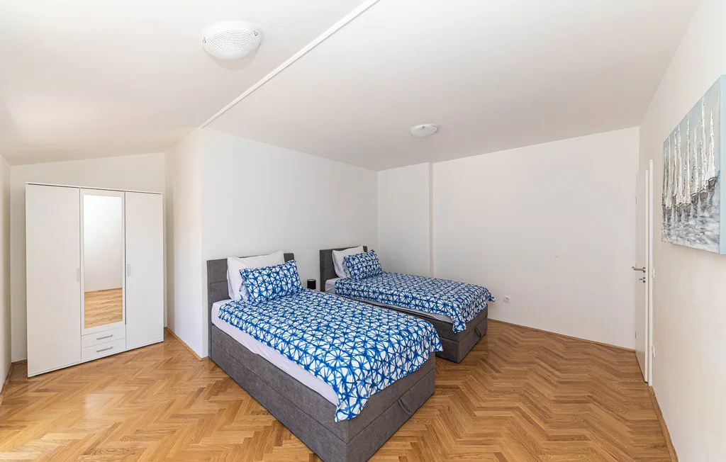 Un dormitorio luminoso con dos camas y ropa de cama azul estampada.