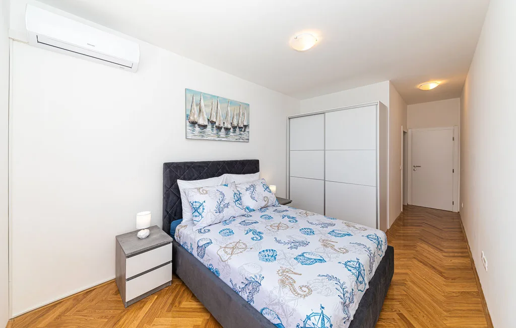 Un dormitorio con una cama, un armario corredizo y suelo con diseño de madera.