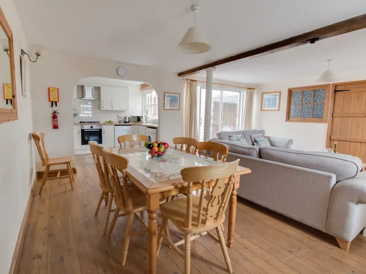 A dining area with a wooden table and seating, beside a living room.