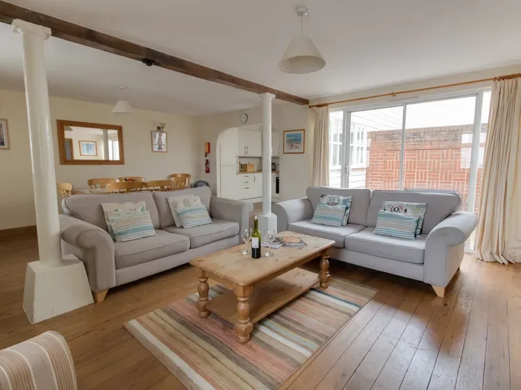 A bright living room with two seating areas around a wooden coffee table.