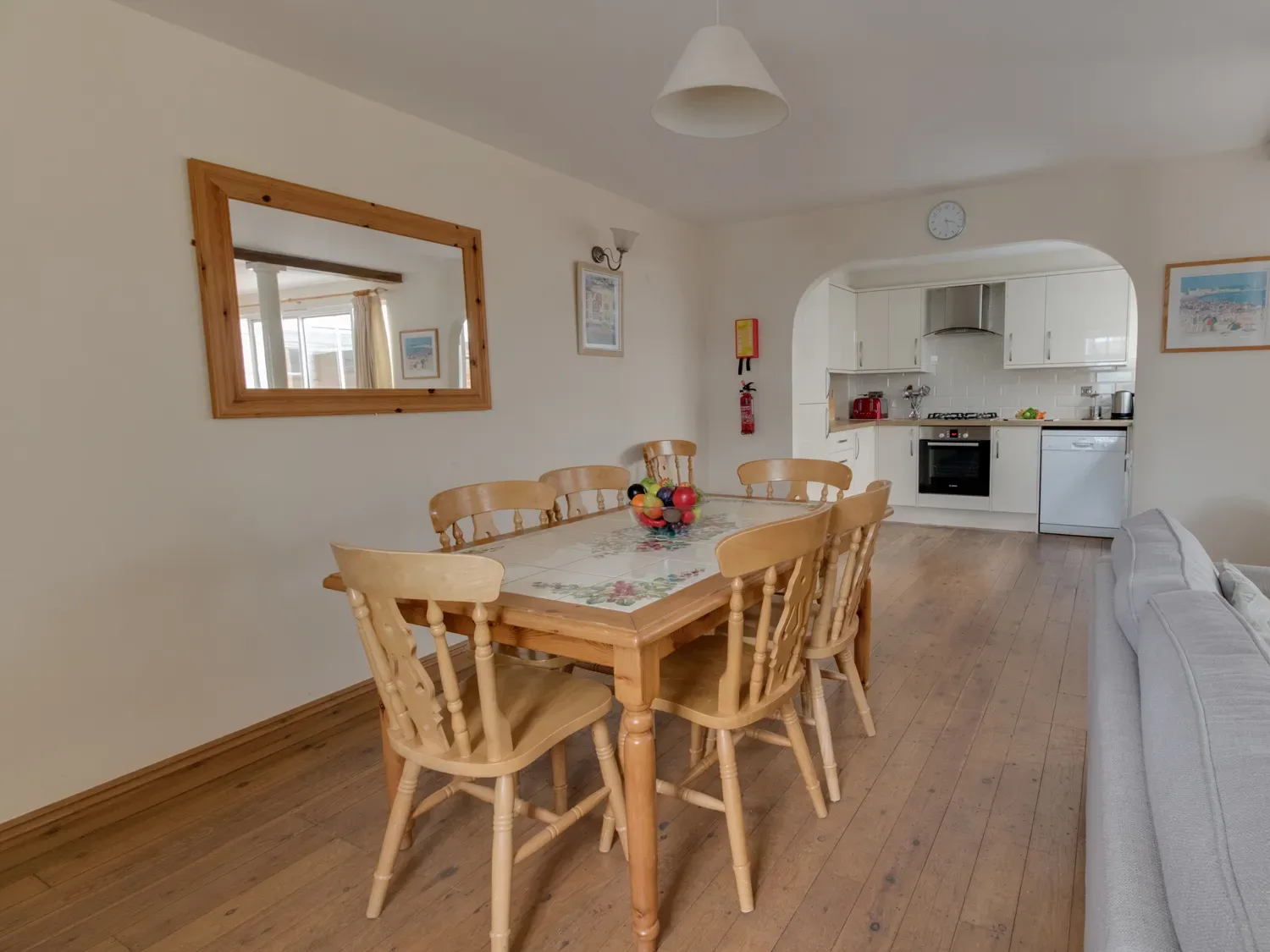 A dining area with a wooden table and seating beside an open kitchen.
