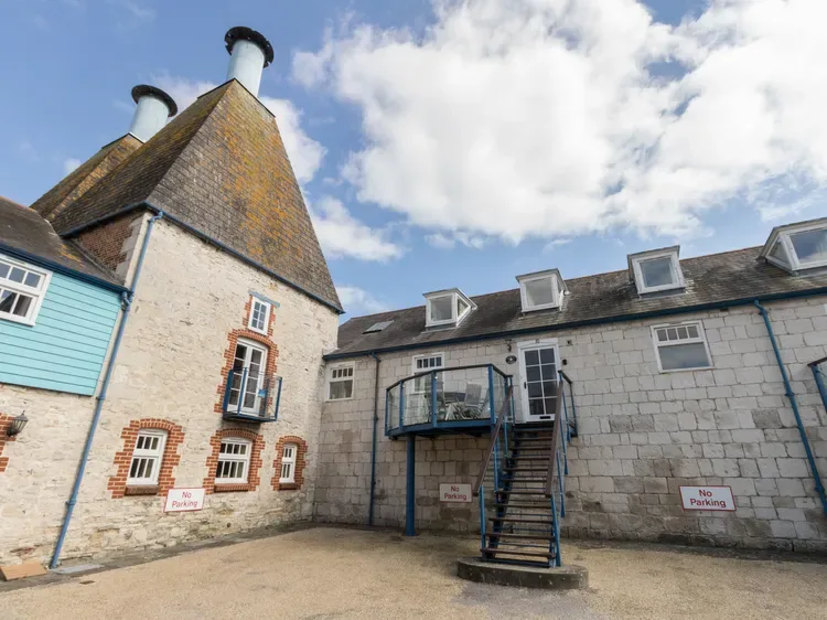 A stone courtyard building with an exterior staircase and blue balcony.