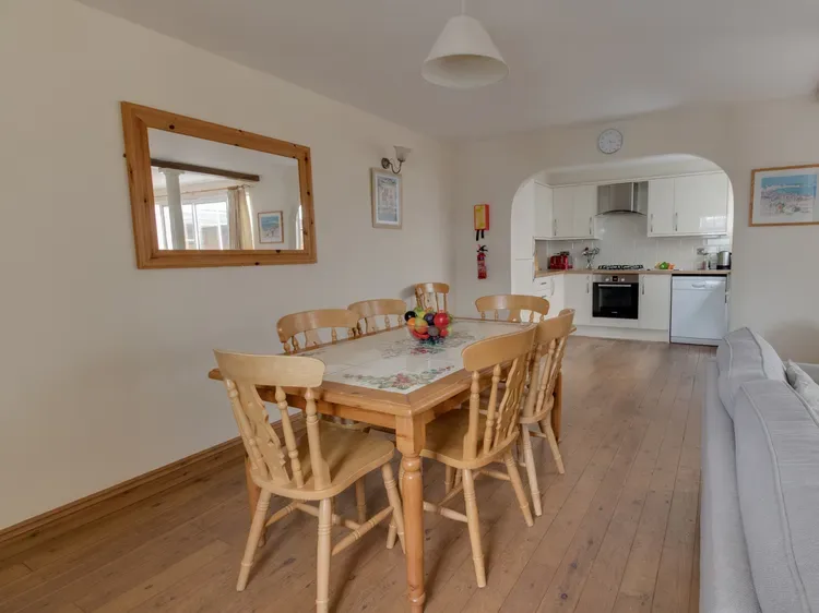 A dining area with a wooden table and chairs beside an open kitchen.