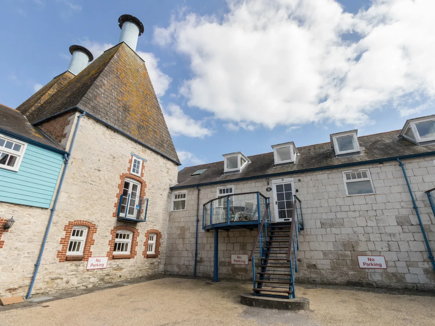 An exterior courtyard with stone buildings a staircase and no parking signs at George's House in Brewers Quay Harbour