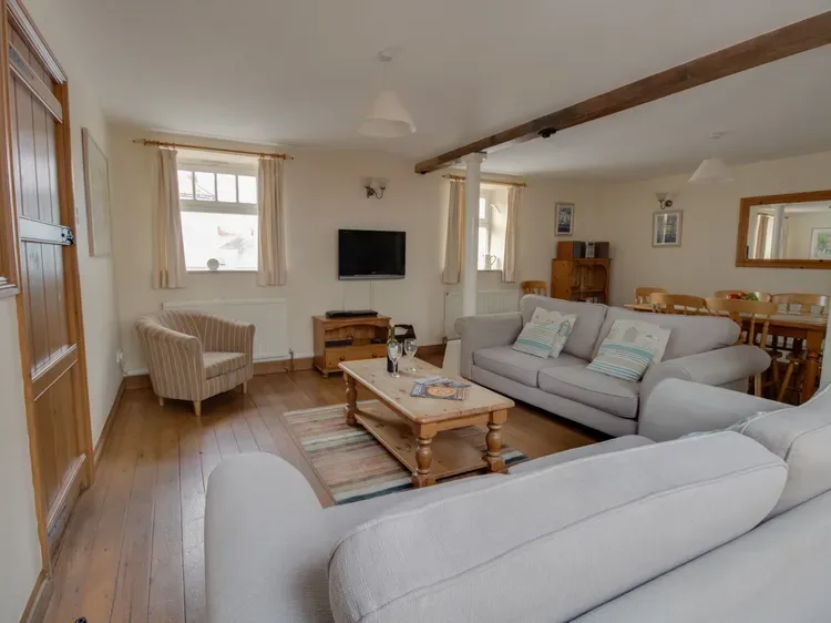 A living room with seating arranged around a coffee table and television.