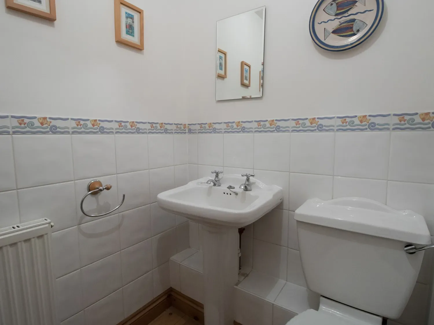 A bathroom with a white sink, toilet, and decorative tile border.