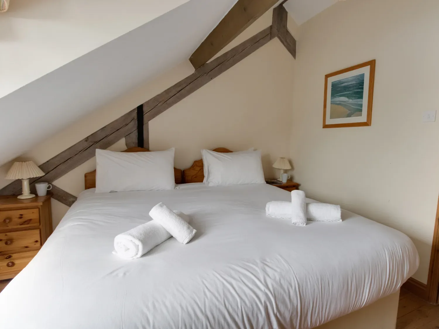 A bedroom with a double bed white linens rolled towels bedside tables lamps and framed artwork at Georges House Brewers Quay Harbour