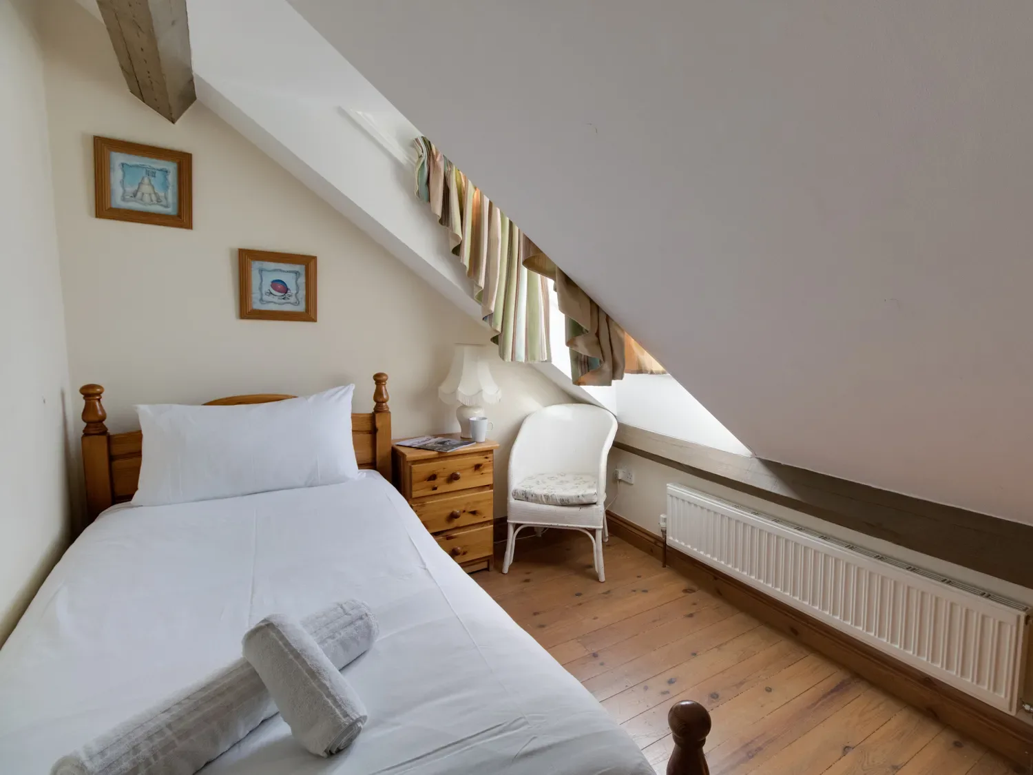 A bedroom with a single bed a wooden nightstand a white chair and a slanted ceiling window at Georges House Brewers Quay Harbour