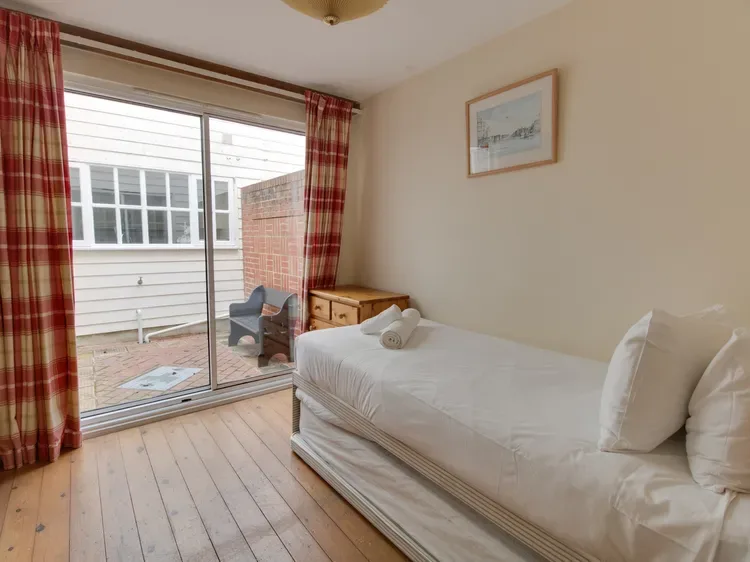 A bedroom with a single bed beside sliding glass doors opening onto a patio.