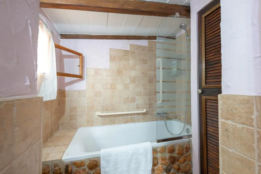 Un baño con bañera, paredes revestidas de azulejos y una ducha.