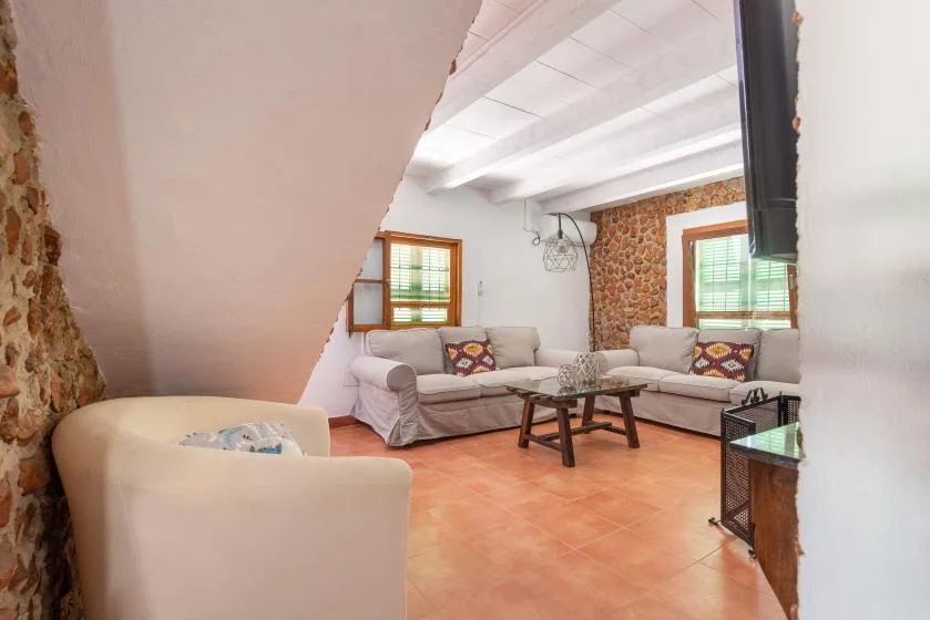 Una sala de estar con asientos, mesas pequeñas y paredes de piedra vista.
