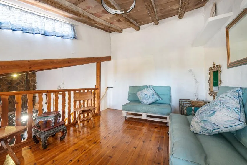 Una sala de estar con asientos color turquesa y vigas de madera expuestas.