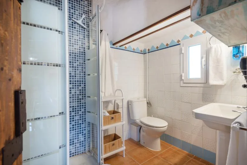 Un baño alicatado con ducha, inodoro y lavabo.