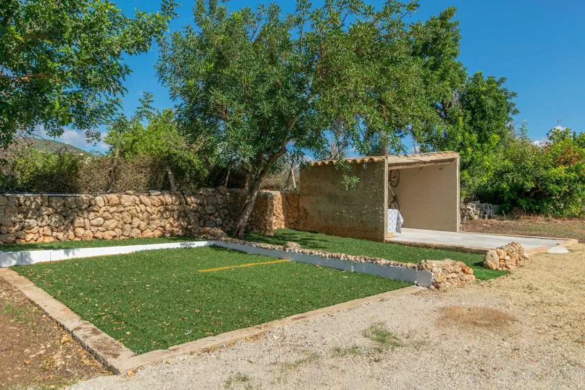 Una zona de césped al aire libre con un muro de piedra y árboles frondosos.