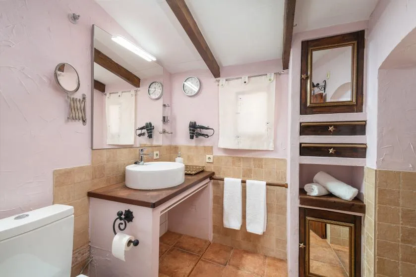 Un baño con lavabo, espejo y paredes revestidas de azulejos.