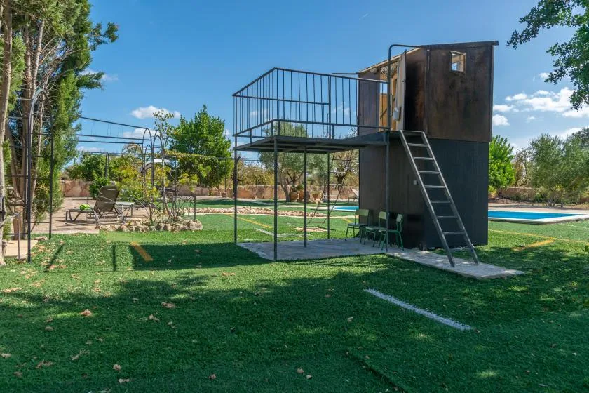 Un jardín al aire libre con una plataforma metálica elevada junto a una piscina.