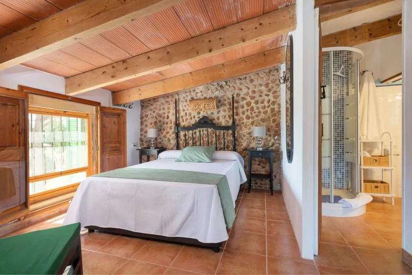 Un dormitorio con dos camas y una pared de piedra.