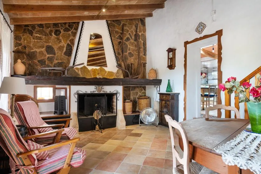 Una sala de estar y comedor rústica con chimenea de piedra y vigas de madera.