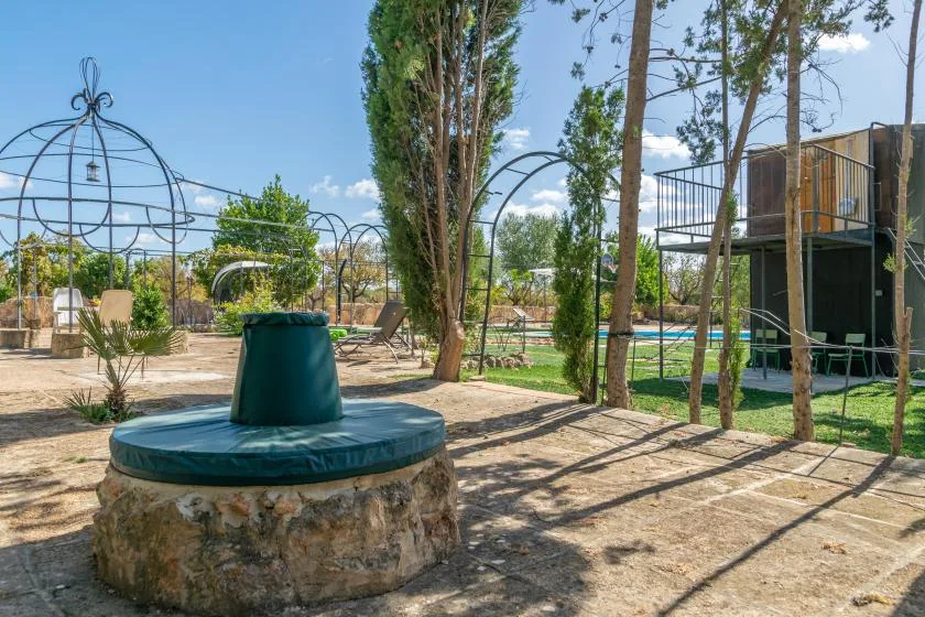 Una zona ajardinada al aire libre con un elemento circular de piedra y una cubierta verde.