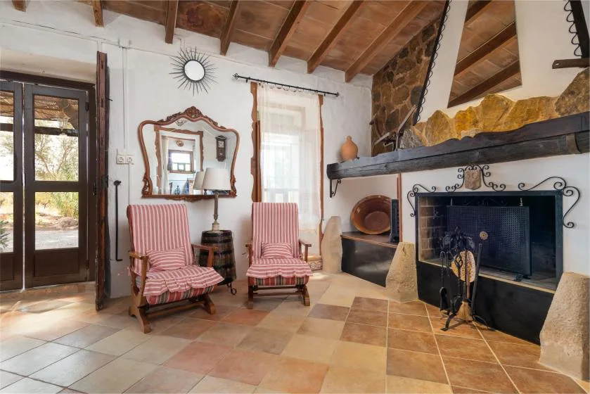 Una sala de estar con dos asientos a rayas junto a una chimenea de piedra.