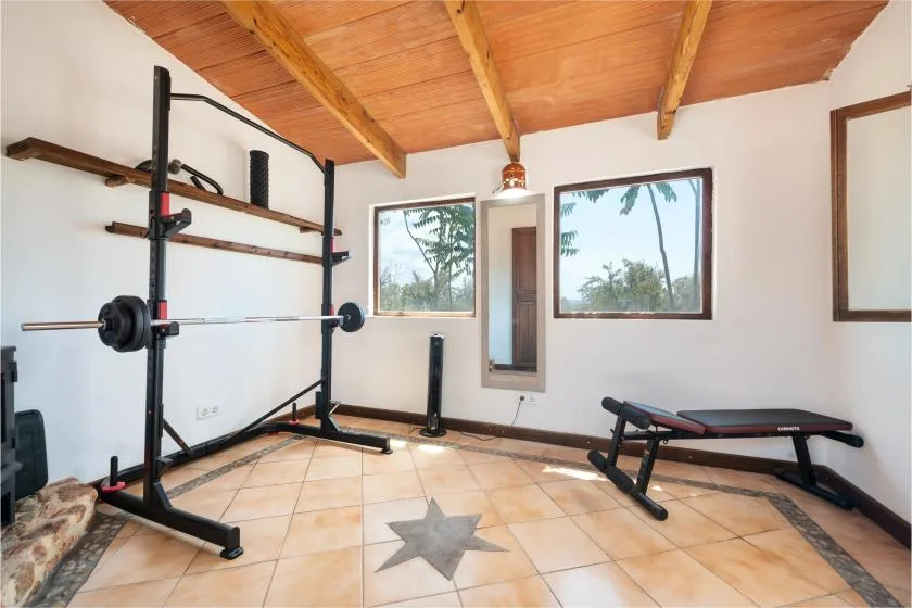 Un gimnasio en casa con un soporte de pesas, una barra y un banco de ejercicio.