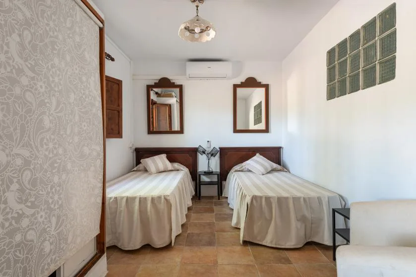 Un dormitorio con dos camas, mesillas y espejos sobre los cabeceros.