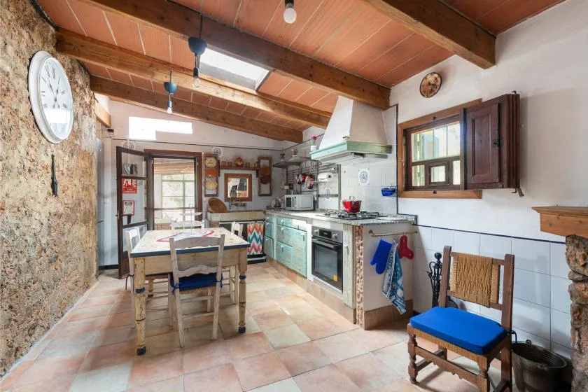 Una cocina y comedor rústicos con vigas de madera a la vista y suelo de baldosas.