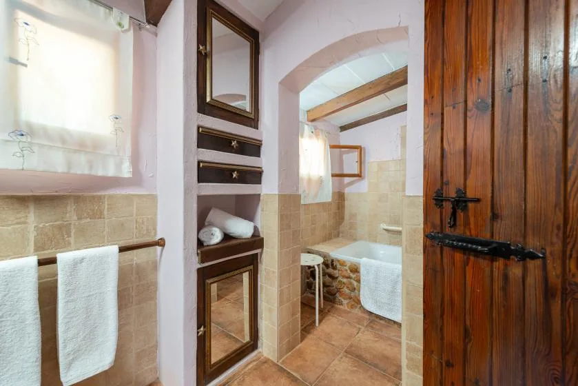 Un baño alicatado con bañera y puerta de madera.