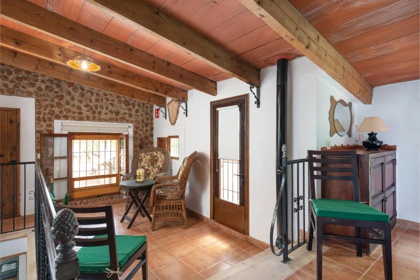 Una sala rústica con vigas de madera a la vista y asientos junto a una ventana.