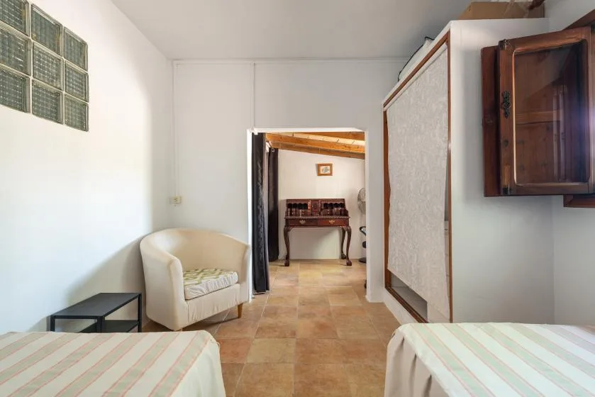 Un dormitorio con dos camas y una puerta que da a una habitación con escritorio.