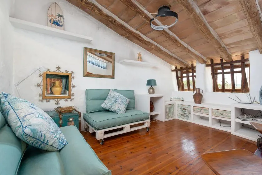 Una luminosa sala de estar abuhardillada con asientos acolchados y vigas de madera.