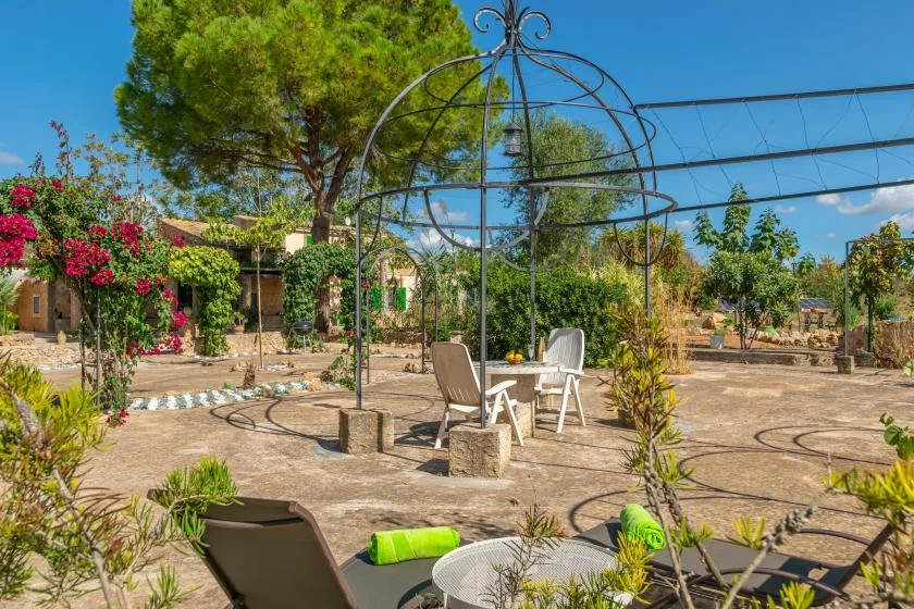 Un patio al aire libre con sillas bajo una estructura metálica decorativa.